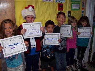 Students holding certificates, one wearing a santa hat