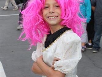 A student wearing a Halloween costume with a wig and smiling