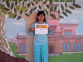 A student smiling and holding up a certificate