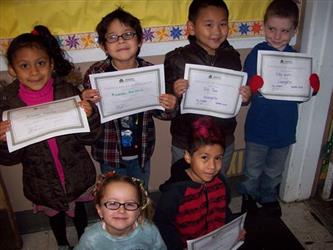 Students standing and sitting showing certificates