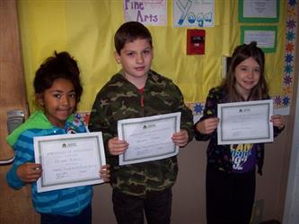 Three students holding up awards certificates
