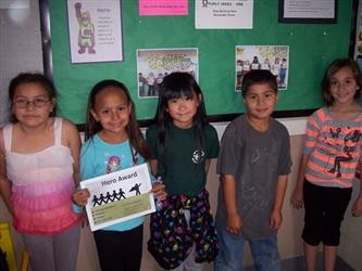 Five students posing in a line, one holding a certificate